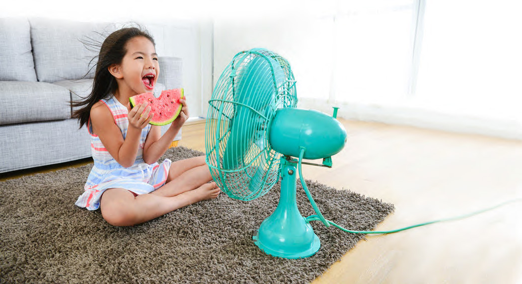 Little girl eating a slice of water melon in front of a blue fan